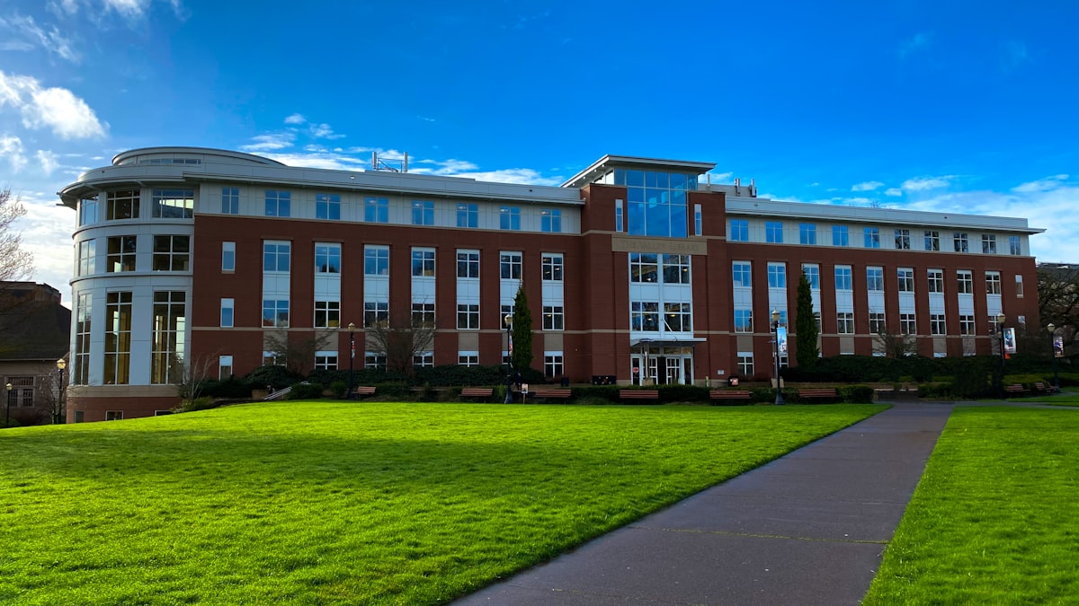 A university campus building behind a green lawn