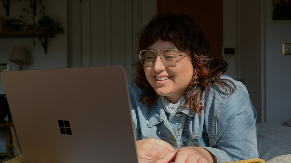 A student smiling during a video interview on a laptop in a bright room